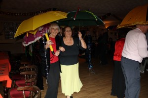 Ann & Pat take part in the brolly parade ('Bourbon Street Parade'). George Tidiman's All Stars at Farnborough Jazz Club 19Dec2014. Photo by Mike Witt.