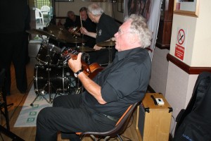 Laurie Chescoe's Reunion Jazz Band at Farnborough Jazz Club 3 July 2015. What an 'engine' aye? (LtoR) Colin Bray (Piano), Jim Douglas (bnjo)), Laurie Chescoe (drms) and Pete Skivington (bass ukulele). Photo by Mike Witt.