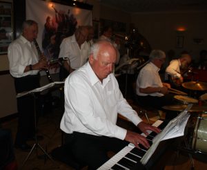 Yerba Buena Celebration Jazz Band seen here at Farnborough Jazz Club (Kent) on 26th June 2016. (front row LtoR) Hugh Crozier (piano), Pete Lay (drums) and Nick Singer (banjo). (Back row, LtoR) Goff Dubber (clarinet),Mike Barry (2nd trumpet &vocals), Dave Rance (1st trumpet &vocals), Graham Wiseman (trombone) and John Arthy (tuba). Photo by Mike Witt.