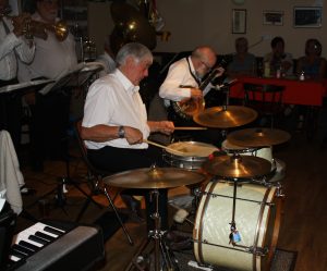 Yerba Buena Celebration Jazz Band seen here at Farnborough Jazz Club (Kent) on 26th June 2016. (LtoR) Dave Rance (band leader, 1st trumpet &vocals), Graham Wiseman (trombone), John Arthy (tuba) (front) Pete Lay (drums) and Nick Singer (banjo). (also pictured - wives Barbara Barry, Heather Lay and Sue Wiseman). Photo by Mike Witt.