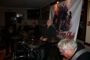 Couldn't resist this one of Laurie's cheeky smile! This is Laurie Chescoe's Reunion Band at Farnborough Jazz Club (Kent) on 22apr2016. (LtoR) Mike Pointon (trombone), Colin Bray (piano), Jim Douglas (banjo/guitar), Laurie Chescoe (drums) and Peter Skivington (bass guitar & bass ukelele). Photo by Mike Witt.
