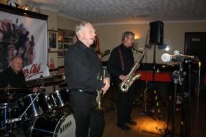 Alan Gresty (trumpet) and Al Nicolls (tenor sax) are driven by John Ellmer on drums with 'Tony Pitt's All Stars' at Farnborough Jazz Club (Kent) on 6th May 2016. Photo by Mike Witt.