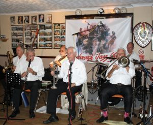 Lord Napier Hotshots play at Farnborough Jazz Club (Kent) on Friday, 29th July 2016. (LtoR) Mick Scrivens (bass sax), Pat Glover (clarinet), John Stewart ( banjo), Mike Jackson (trumpet), Mike Duckworth (trombone&fab socks) and Bill Traxler (drums). Photo by Mike Witt.