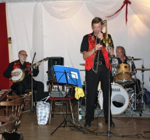 Bill Todd takes a solo for Phoenix Dixieland Jazz Band at Farnborough Jazz Club on Friday, 19th August 2016. (LtoR) John Stuart (banjo), Bill Todd (trombone) and Alan Clarke (drums). Photo by Mike Witt.